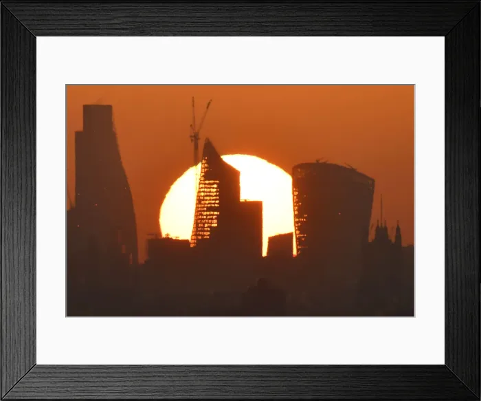Framed Print : Sun is seen rising over skyscrapers in the City of London financial district in London