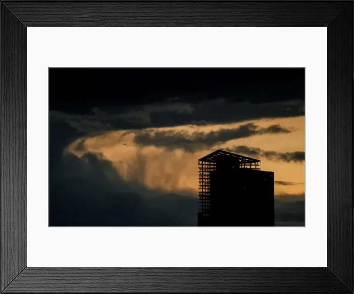 Framed Print : An aircraft flies past a building under construction on a stormy evening in Moscow