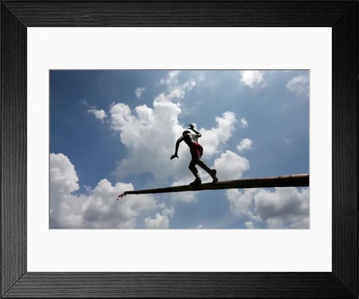 Framed Print : A boy climbs up a greasy pole in a climbing competition at a part of Sinhala Framed Print : A boy climbs up a greasy pole in a climbing competition at a part of Sinhala