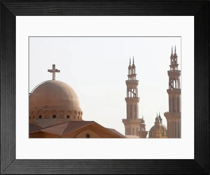 Framed Print : Minarets of a mosque and the cross above a church is seen during the Muslim holy fasting