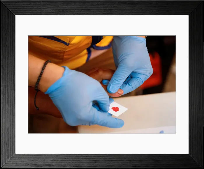 Framed Print : A paramedic takes a blood sample for DNA testing from a resident looking for a relative Framed Print : A paramedic takes a blood sample for DNA testing from a resident looking for a relative