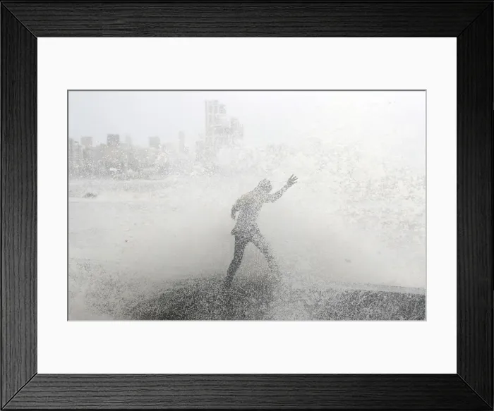 Framed Print : A man loses his balance as he gets drenched by a large wave during high tide at a