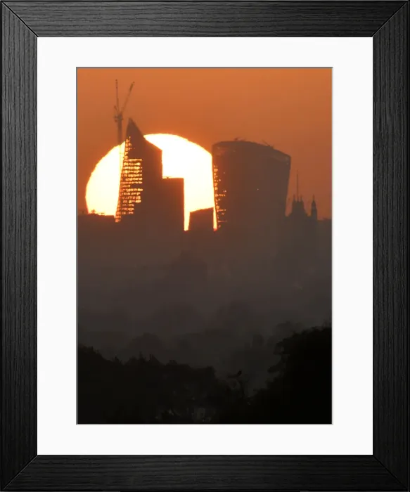 Framed Print : The sun is seen rising over skyscrapers in the City of London financial district in Framed Print : The sun is seen rising over skyscrapers in the City of London financial district in