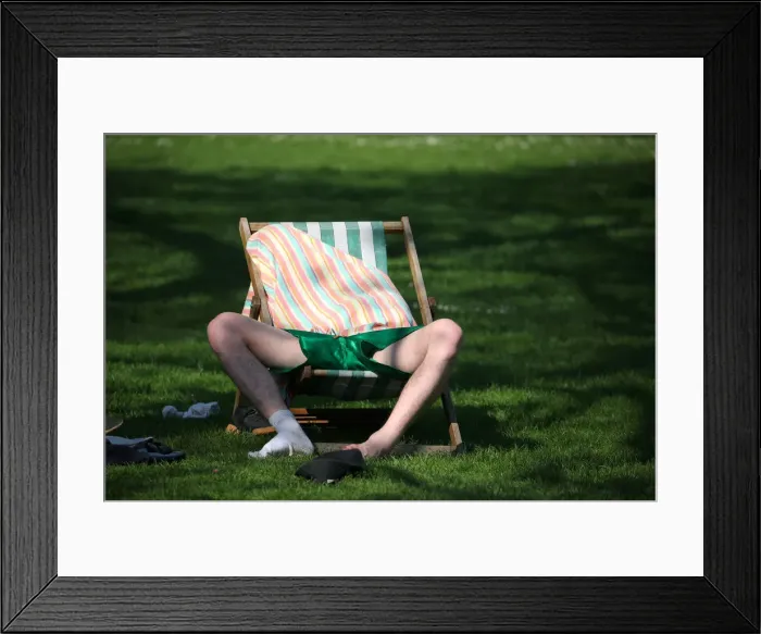 Framed Print : A man relaxes in the sunshine in St James Park in central London Framed Print : A man relaxes in the sunshine in St James Park in central London