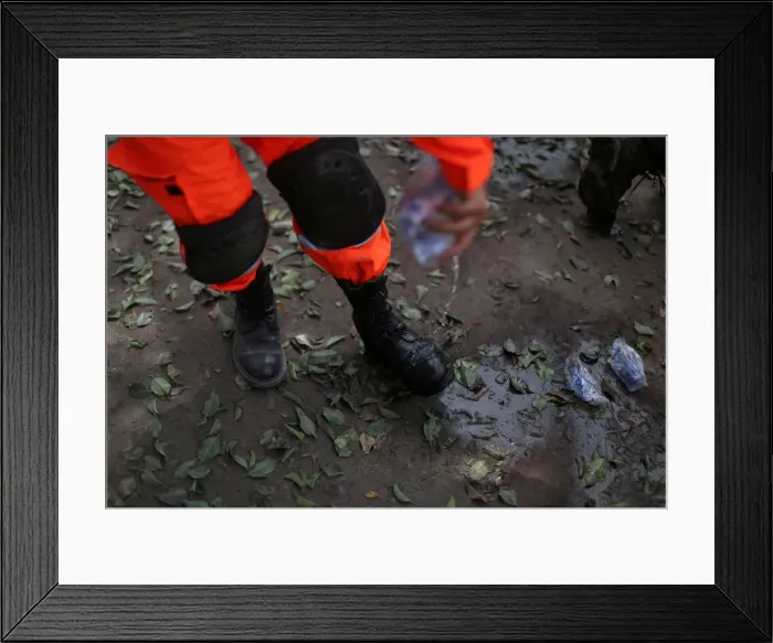 Framed Print : A rescue worker cools off his boots with water near an area affected by the eruption of Framed Print : A rescue worker cools off his boots with water near an area affected by the eruption of