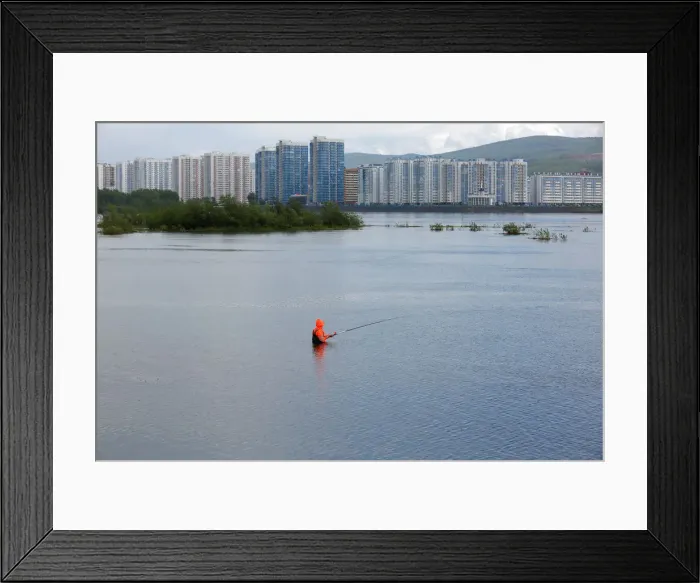 Framed Print : A fisherman stands in the waters of the Yenisei River in the Siberian city of Krasnoyarsk