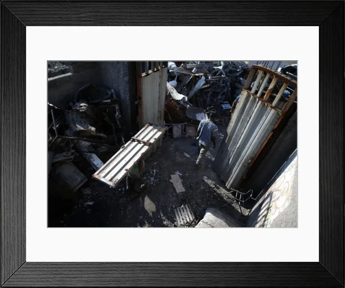 Framed Print : A man carries a piece of metal in a scrapyard in Port-au-Prince