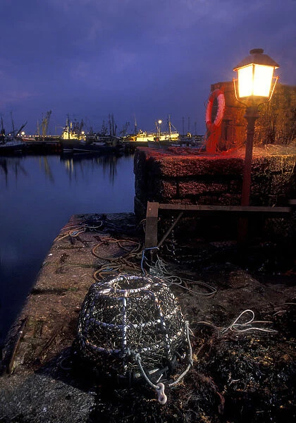 Lobster pot lit by harbour light at night, Newlyn, Cornwall