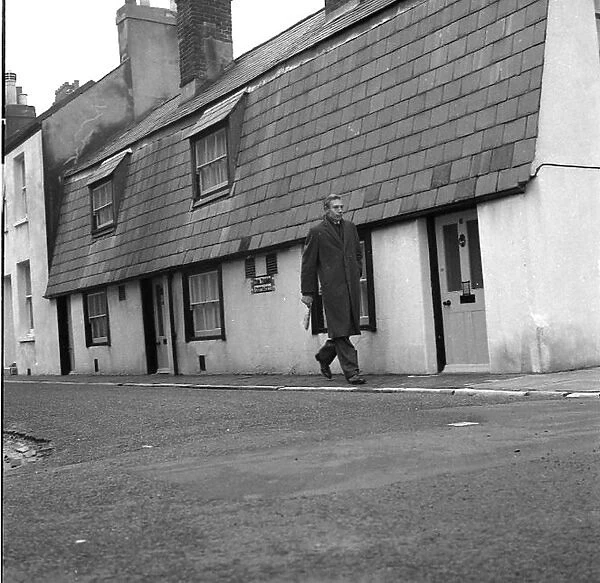 Man walking past Tom Thumb cottages, Eastbourne