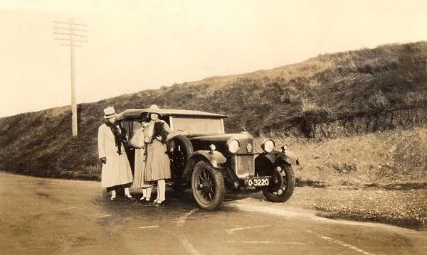 Women standing by large car