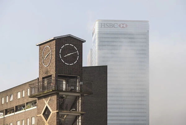 Chrisp Street Clock Tower with Canary Wharf in background, London, UK