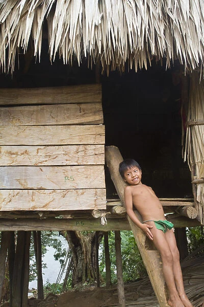 Panama, Chagres River, Embera Village, Embara boy leaning against traditional thatched