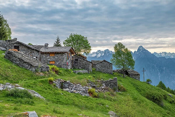 Traditional stone huts with high peak Pizzo di Prata in background, Alpe Buglio