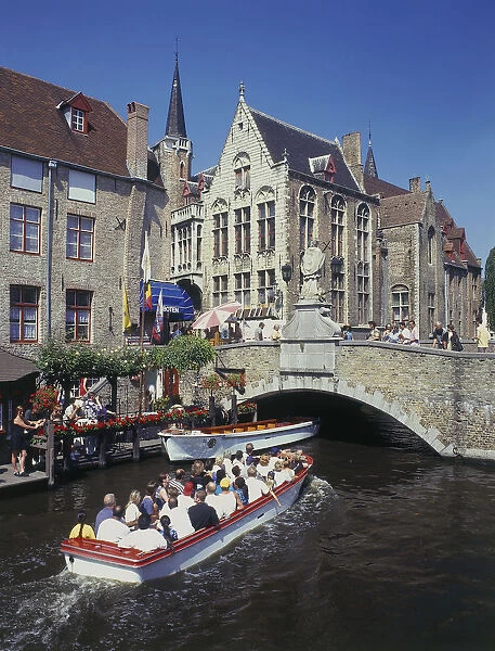 10080983. BELGIUM West Flanders Bruges Tourists on boat trips on a canal with old bridge