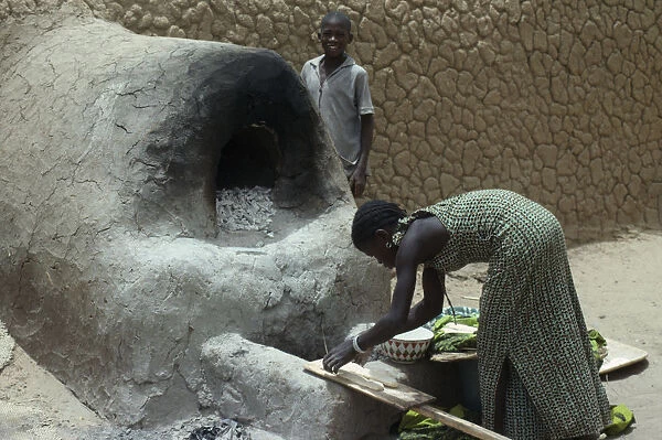 20075145. MALI Timbuctu Girl making bread using outside clay oven