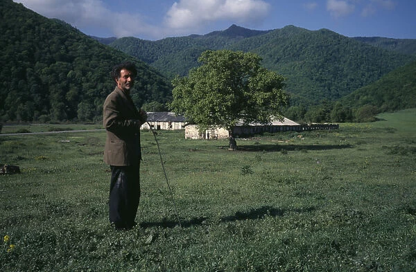 20084415. ARMENIA Getashen Man standing in rural landsape with low stone building behind