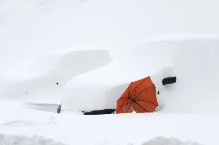 Framed Print : An abandoned red umbrella is supported by two cars covered in snow in the village of