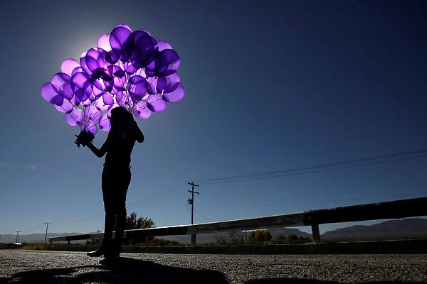 Activist holds purple balloons at El Navajo creek during a ceremony to mark the