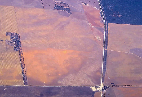 An aerial view of a house and intersecting roads amongst agricultural farming land