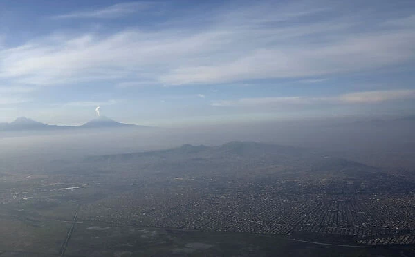 An aerial view of Mexico City is seen, with the Popocatepetl volcano in the background