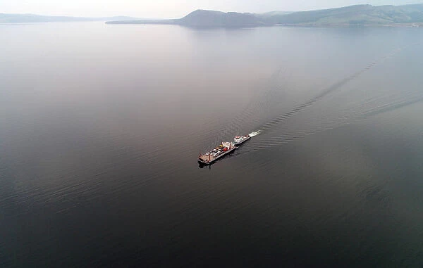 Aerial view shows a ferry transporting passengers and vehicles across the Yenisei