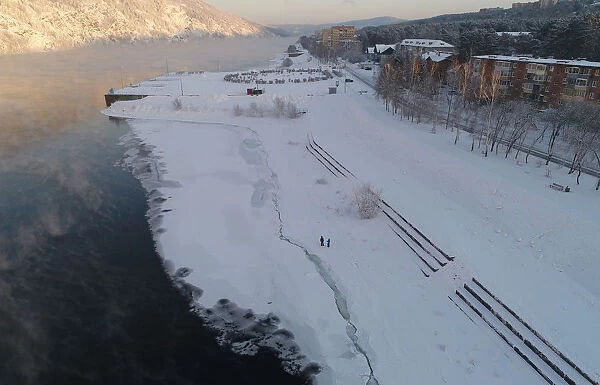 An aerial view shows people walking on the bank of the Yenisei River in Divnogorsk
