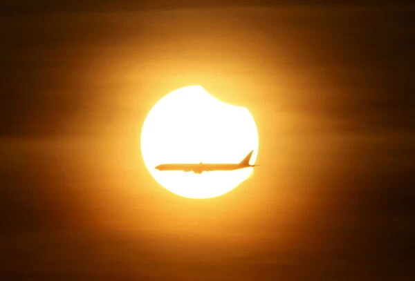 An aeroplane flies past the sun as it goes into a partial solar eclipse in Singapore