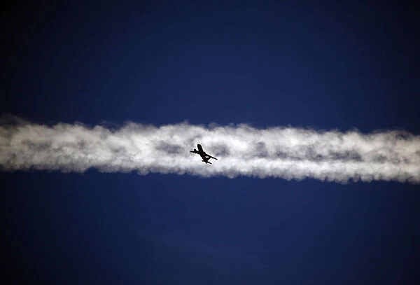 An aeroplane flies underneath the jet stream of another aircraft above the Italian city