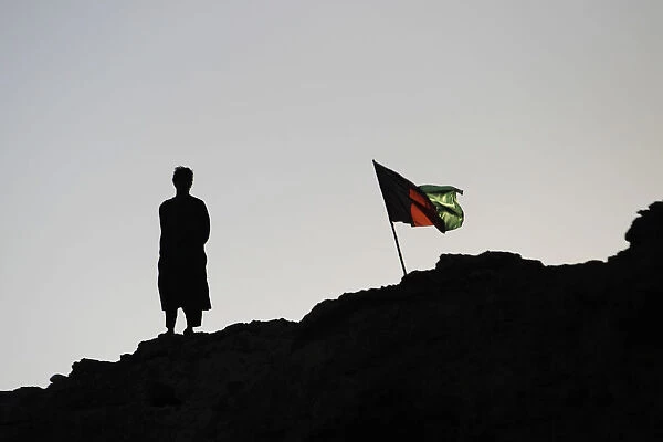 An Afghan policeman stands beside the national flag in southern Afghanistans Helmand