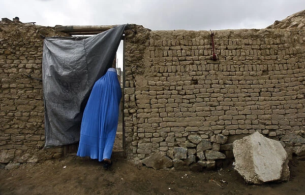 Afghan woman clad in burqa enters a house in Kabul