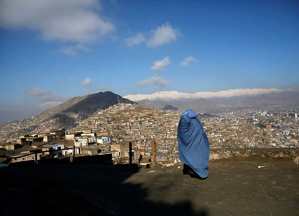An Afghan woman walks on a hilltop overlooking Kabul