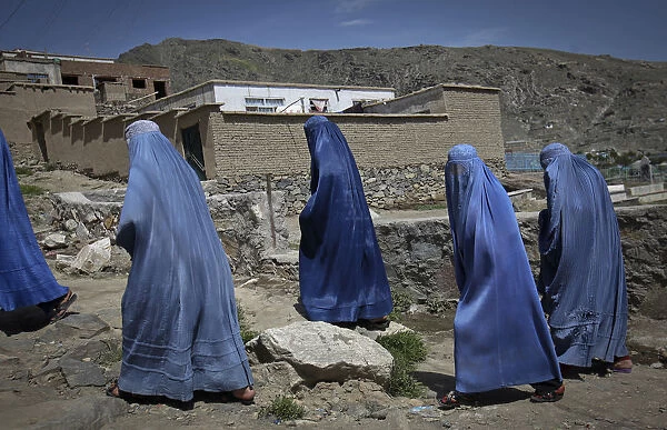 Afghan women clad in burqa walk up a hill at the old part of Kabul