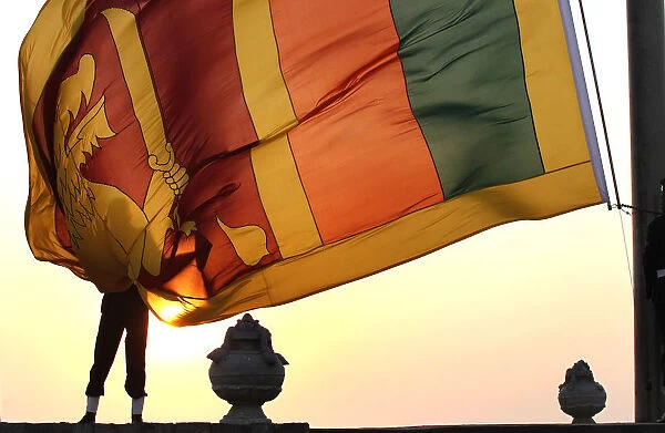 An air force officer holds the Sri Lanka national flag as the sun sets at galle face