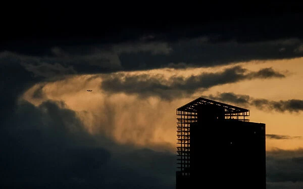 An aircraft flies past a building under construction on a stormy evening in Moscow