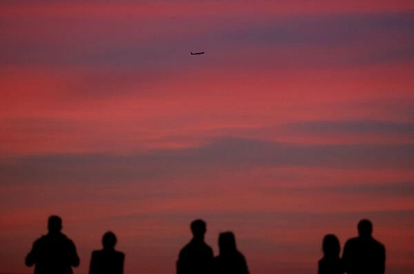 An aircraft flies as people watch sunset in Moscow