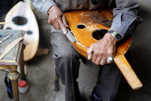 Artisan Mohammed Karam works on an oud in front of a workshop in Cairo