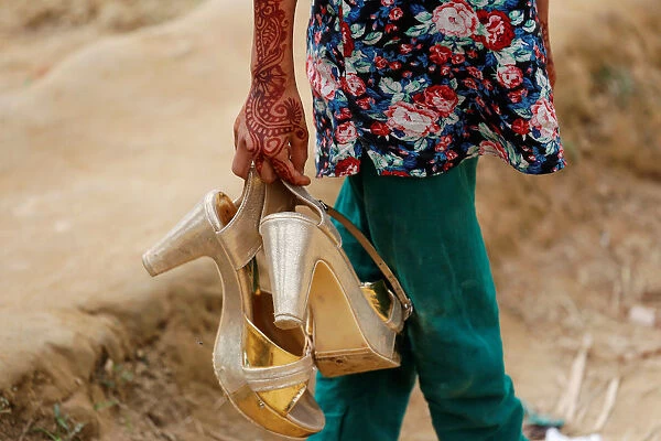 A Bangladeshi girl carries her older sisters golden shoes as their family visits