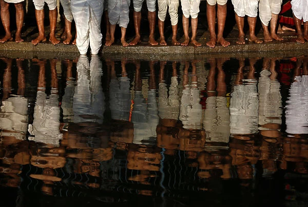 Bare feet of devotees are pictured as they stand on the bank of the Hanumante River while