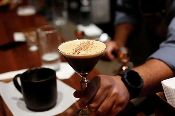 A bartender serves an espresso martini to a customer at the mixology bar as Starbucks