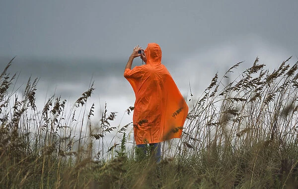 A beach goer photographs the storm surf from the dunes a day before the landfall of