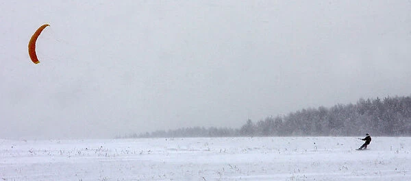 A Belarussian kiteboarder enjoys cold windy weather near the village of Rakov