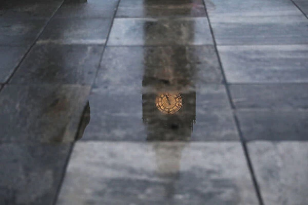 Big Ben is reflected in the wet pavement in London