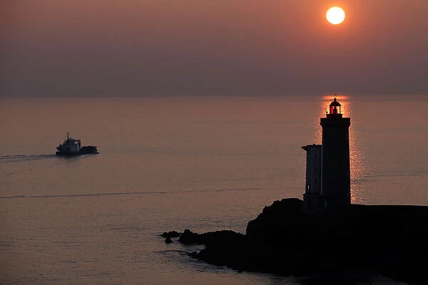 A boat makes his way behind the Phare du Petit Minou as the sun sets over the Atlantic