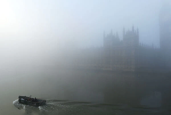 A boat on the River Thames passes the Houses of Parliament, in heavy fog in central