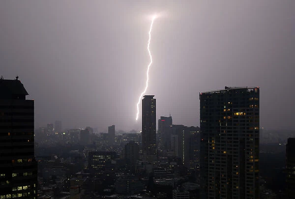 A bolt of lightning strikes over Tokyo skyscrapers at dusk in Tokyo
