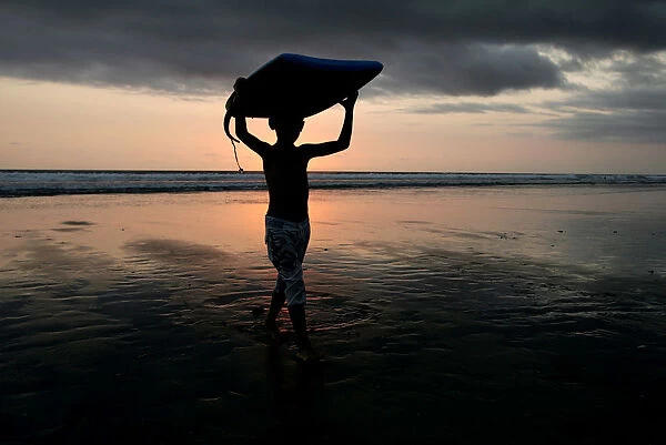 A boy carries his boogie board near Kuta beach on the Indonesian resort island of Bali