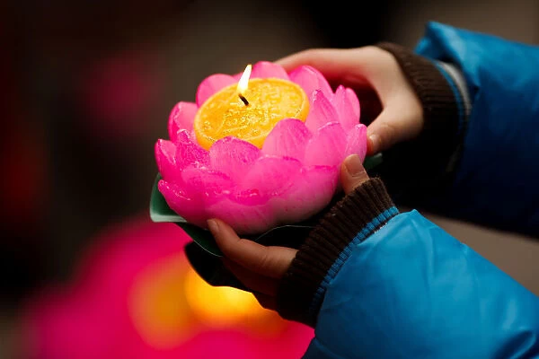 A boy holds a candle to pray at a Buddhist temple in Badachu park during Spring Festival