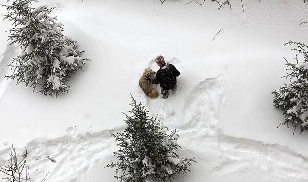 A boy plays with his dog in a snow-covered park in Ankara