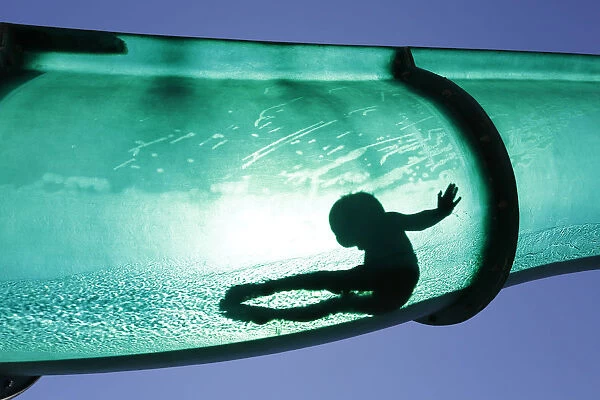 A boy slides down a water chute in a public swimming pool in Thun