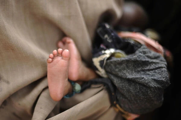 A bundled-up baby rests as Somali refugees arrive by bus to the reception center at
